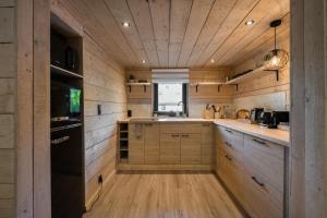 a kitchen with wooden cabinets and a black refrigerator at Wood Chalet Durbuy in Durbuy
