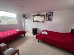 a hotel room with two beds and a mirror at Alojamiento Sabadell Ibarra in Ibarra