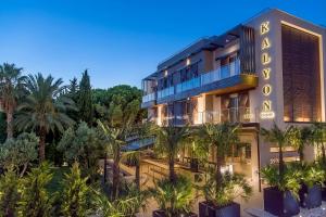 an exterior view of a hotel with palm trees at Kalyon Cesme in Çeşme