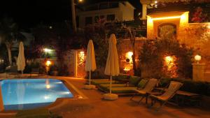 a swimming pool at night with umbrellas and chairs at Villa Grande Kalkan in Kaş