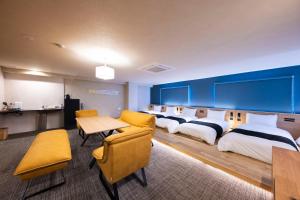 a hotel room with four beds and a table and chairs at ホテル雅々音 in Sasebo