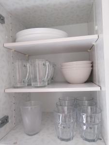 a kitchen shelf with bowls and plates and glasses at La Doudou Maison à louer in Mons