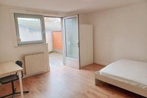 a bedroom with a bed and a desk and a window at La Doudou Maison à louer in Mons