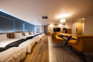 a hotel room with a row of beds and a table at ホテル雅々音 in Sasebo