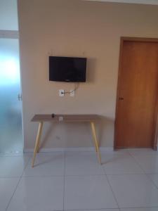 a wooden table with a television on a wall at Hospedaria São Francisco in Cachoeira Paulista