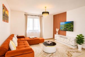 a living room with an orange couch and a tv at Stylish 2BR Apartment Free WiFi Near Nairobi National Park in Ongata Rongai 