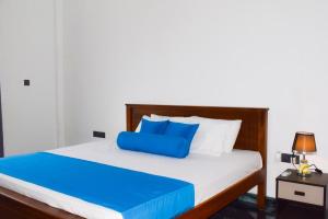 a bed with a blue pillow on top of it at JK Residence Trincomalee in Trincomalee +5 photos