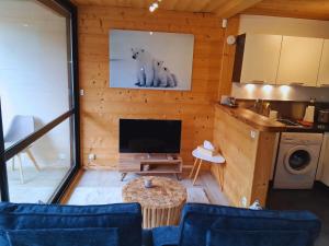 a living room with a tv and a table and a kitchen at Whitebearlodge in Arâches-la-Frasse