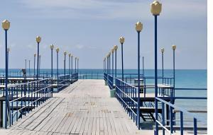 a wooden pier with tables and lights on the ocean at Ak-Kalpak in Cholpon-Ata