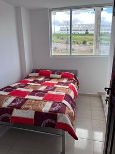 a bed sitting in a room with a window at Alojamiento Sabadell Ibarra in Ibarra +5 photos