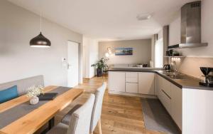 a kitchen and dining room with a wooden table at WEINBERG APARTMENTS & Brixen Südtirol Guest Pass in Natz-Schabs