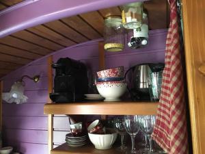 a purple room with a shelf with dishes and glasses at La Roulotte du Fier in Annecy +9 photos