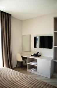 a hotel room with a desk with a tv and a bed at Rodi Hotel Elbasan in Elbasan