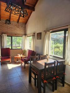 a dining room with a table and chairs and windows at Atardecer Serrano in Villa General Belgrano
