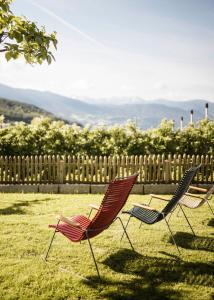 three chairs sitting in the grass in a yard at WEINBERG APARTMENTS & Brixen Südtirol Guest Pass in Natz-Schabs