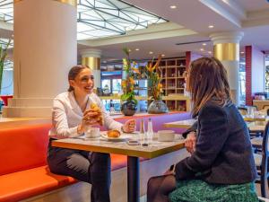 two women sitting at a table in a restaurant at Mercure Lyon Est Villefontaine in Villefontaine