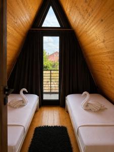 zwei Betten in einem Zimmer mit Fenster in der Unterkunft Ocna Frame - A Frame cu Jacuzzi si Terasa in Ocna-Mureşului