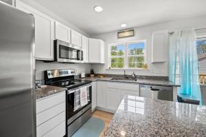 a kitchen with white cabinets and a stove top oven at Casa Playa in Greenbackville +31 photos