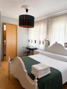 a bedroom with a large white bed with a green blanket at Hostal Porta Santiago in Lugo