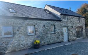 a stone cottage with a white door and windows at Storws Tanrallt in Holyhead