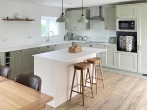 a kitchen with white cabinets and a island with stools at Storws Tanrallt in Holyhead