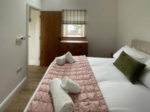 a bedroom with a pink and white bed with towels on it at Storws Tanrallt in Holyhead