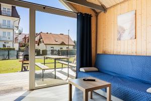 a living room with a blue couch and a large window at Domki Anchor II - 200m od Morza, Klimatyzacja, Plac Zabaw, Parking in Karwia