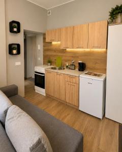 a kitchen with wooden cabinets and a white refrigerator at MieszkaStreet kawalerka in Gniezno