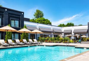 a pool with chairs and umbrellas next to a building at Country Inn & Suites by Radisson, Seattle-Bothell, WA in Bothell