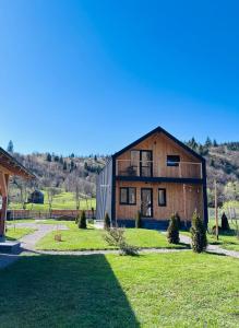 a large wooden barn with a grass yard at The Black Barn in Frumosu