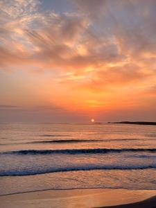 a sunset on the beach with the ocean at Entire home in Belmullet in Belmullet +3 photos