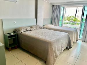 a hotel room with two beds and a window at Flat JP Beira mar in João Pessoa +34 photos