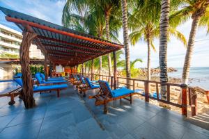 a deck with chairs and palm trees on the beach at Hotel Meson de Mita in Punta Mita