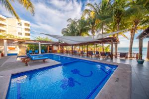 a swimming pool with a hammock and the ocean at Hotel Meson de Mita in Punta Mita