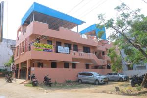 a pink building with cars parked in front of it at Yardlin Hotel in Perunkalattu