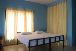 a bed in a room with windows with curtains at Yardlin Hotel in Perunkalattu
