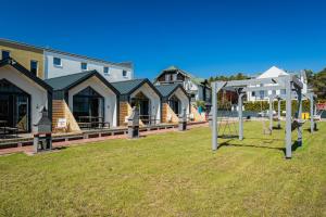 a group of houses with a playground in a yard at Domki Anchor II - 200m od Morza, Klimatyzacja, Plac Zabaw, Parking in Karwia