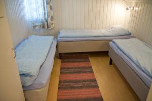 two twin beds in a small room with a rug at Erkin Haussi in Ilmajoki