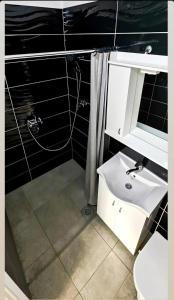 a bathroom with a white sink and black tiles at Sobe i apartmani "Terasa" in Smederevo