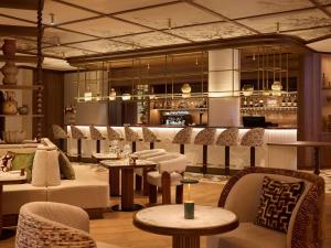 a lobby with chairs and tables and a bar at Grand Hôtel Roi René Aix - MGallery Collection in Aix-en-Provence
