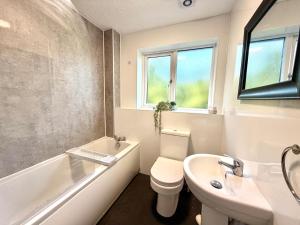 a bathroom with a toilet and a sink and a bath tub at Swan View House in Littleport