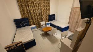 a room with two beds and a table and chairs at Relaxing bed Ajman in Ajman 