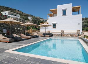 a villa with a swimming pool with chairs and umbrellas at Miles Away Residences in Platis Gialos