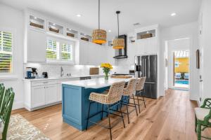 a kitchen with white cabinets and a blue island with stools at The Luxe Sunshine Villa w Private Pool House in West Palm Beach