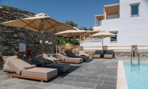 a group of chairs and umbrellas next to a pool at Miles Away Residences in Platis Gialos