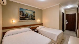a room with two beds and a painting on the wall at Cedro Hotel in Londrina +40 photos