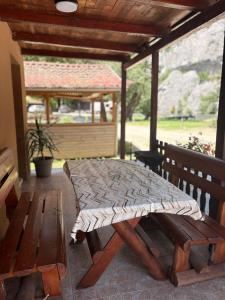 a picnic table and bench on a porch with a gazebo at Riverside Cabin in Železnička Stanica Ovčar Banja