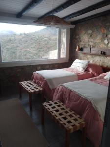 a bedroom with two beds and a large window at Oveja Mansa in La Cumbre