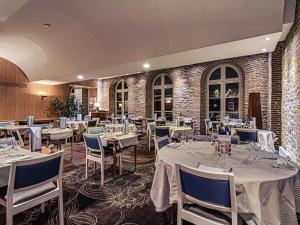 a restaurant with white tables and chairs and a brick wall at Mercure Albi Rives du Tarn in Albi +59 photos