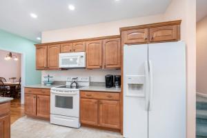 a kitchen with wooden cabinets and a white refrigerator at Fairway Stay in Greenbackville